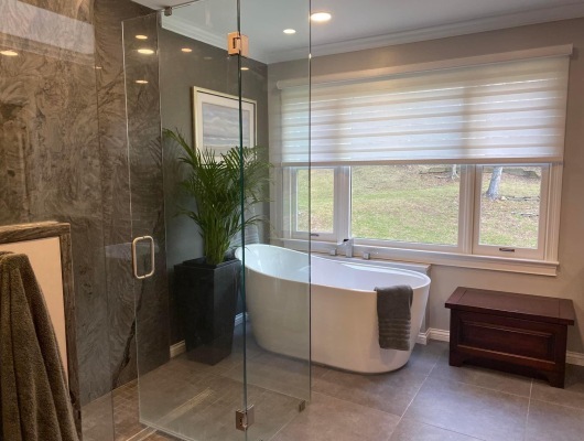 bathroom with glass door, tub, and large window